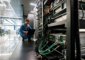 Técnico de DataRoad en un pasillo del centro de datos junto a los armarios de red