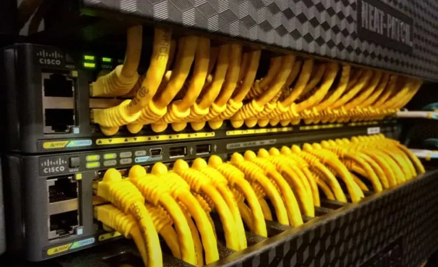 Fila de conmutadores de red de Cisco con numerosos cables Ethernet amarillos conectados.